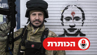 חייל אוקראיני לצד גרפיטי עם תמונת פוטין שרוף בסטויאנקה, אוקראינה