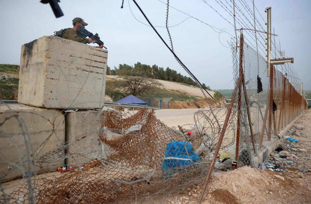 An IDF soldier stands guard near a gap in the partition fence near Hebron 