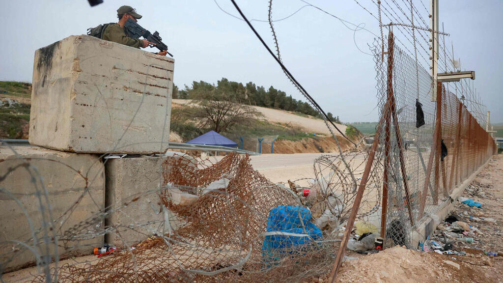 An IDF soldier stands guard near a gap in the partition fence near Hebron 