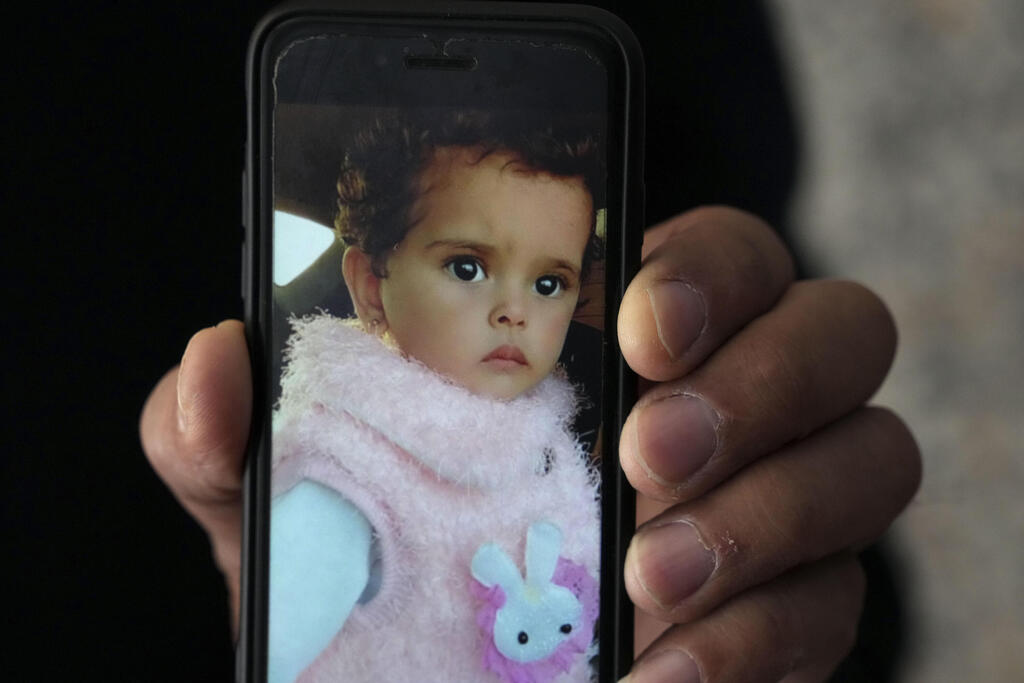 Jalal al-Masri, father of 19-month-old Fatma, who was diagnosed with a congenital heart defect in December 2021, and died as the family waited another three months for an Israeli permit to take her for treatment outside the Gaza Strip, shows her photos at his phone, in Khan Younis, southern Gaza Strip, April 12, 2022