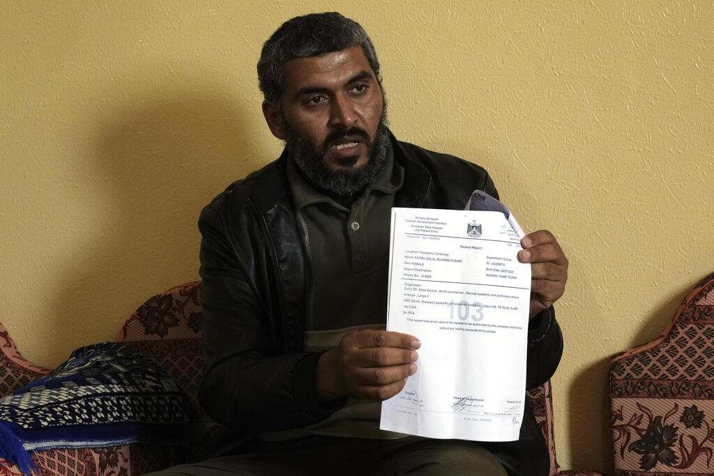 Al-Masri holds a medical report for his daughter Fatma, in Khan Younis, southern Gaza Strip, April 12, 2022