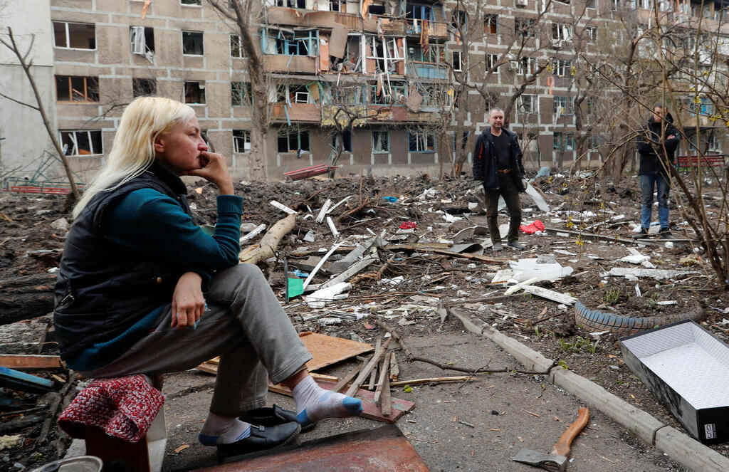 A resident of Mariupol sets outside apartment blocks heavily damaged by Russian shelling 