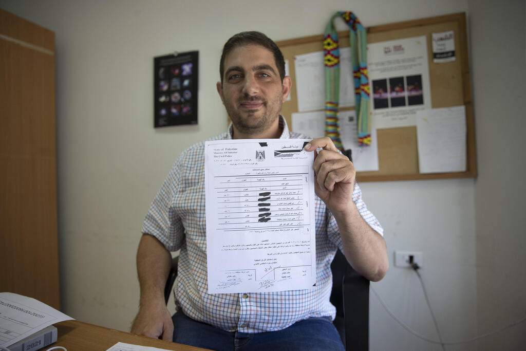 Palestinian American civil society activist Ubai Aboudi holds a copy of the Palestinian police report that includes the investigation and charges against him, at his office in the West Bank city of Ramallah, July 14, 2021