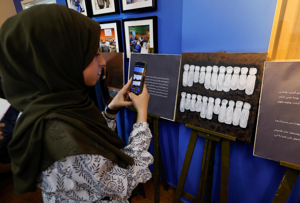 Palestinian girl takes a picture during an exhibition of Zainab al-Qolaq, 22-year-old Gazan artist, in Gaza City May 24, 2022