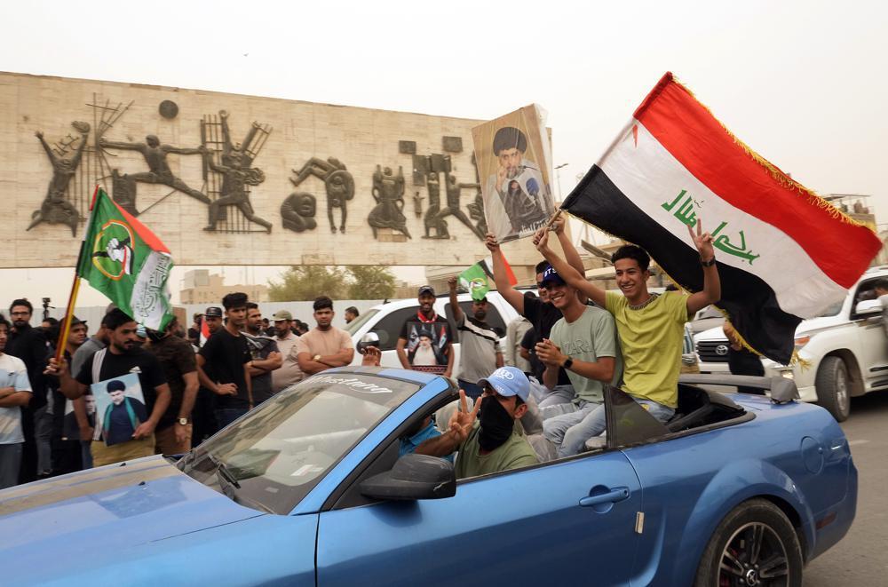 Followers of Shiite cleric Muqtada al-Sadr hold posters with his photo as they celebrate the passing of a law criminalizing the normalization of ties with Israel, in Tahrir Square, Baghdad, Iraq, May 26, 2022