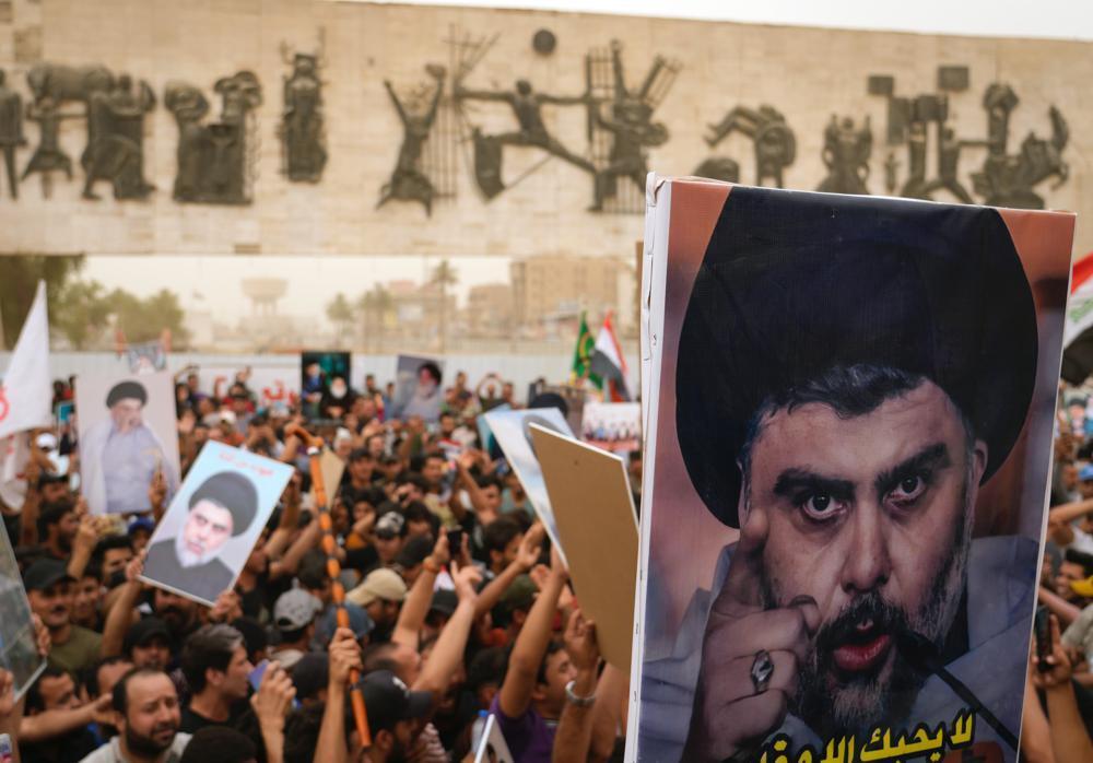 Followers of Shiite cleric Muqtada al-Sadr hold posters with his photo as they celebrate the passing of a law criminalizing the normalization of ties with Israel, in Tahrir Square, Baghdad, Iraq, May 26, 2022