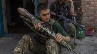 חייל אוקראיני שמאבטח צוות רפואי מנקה את נשקו במחוז דונייצק חבל דונבאס אוקראינה מלחמה רוסיה