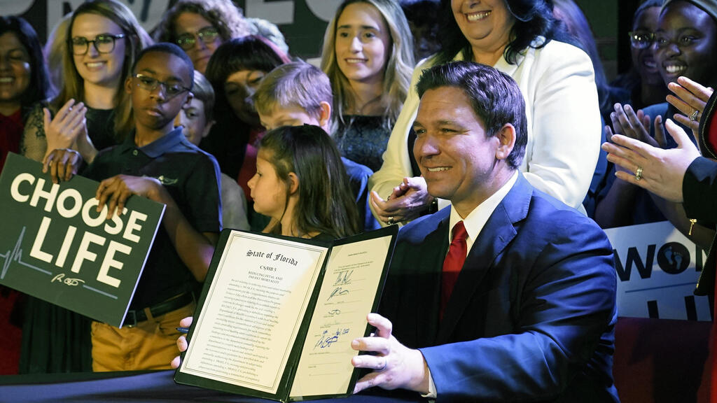 Florida Gov. Ron DeSantis holds up a 15-week abortion ban law after signing it on April 14, 2022, in Kissimmee, Fla