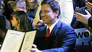 Florida Gov. Ron DeSantis holds up a 15-week abortion ban law after signing it on April 14, 2022, in Kissimmee, Fla