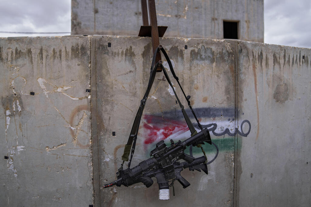 IDF weapons hangs over a Palestinian flag drawn on the wall in the urban warfare training facility 