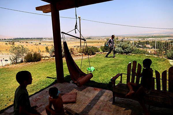 Shlomo Sarid works at his garden next to his kids at the Israeli settlement of Givaat Saleit in Jordan Valley