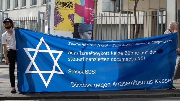 Demonstrators stand with a banner on the topic of "Anti-Semitism in Art" 