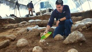 כפיר ארביב, מנהל החפירה מטעם רשות מהעתיקות, מנקה את אחת מאבני הקלע