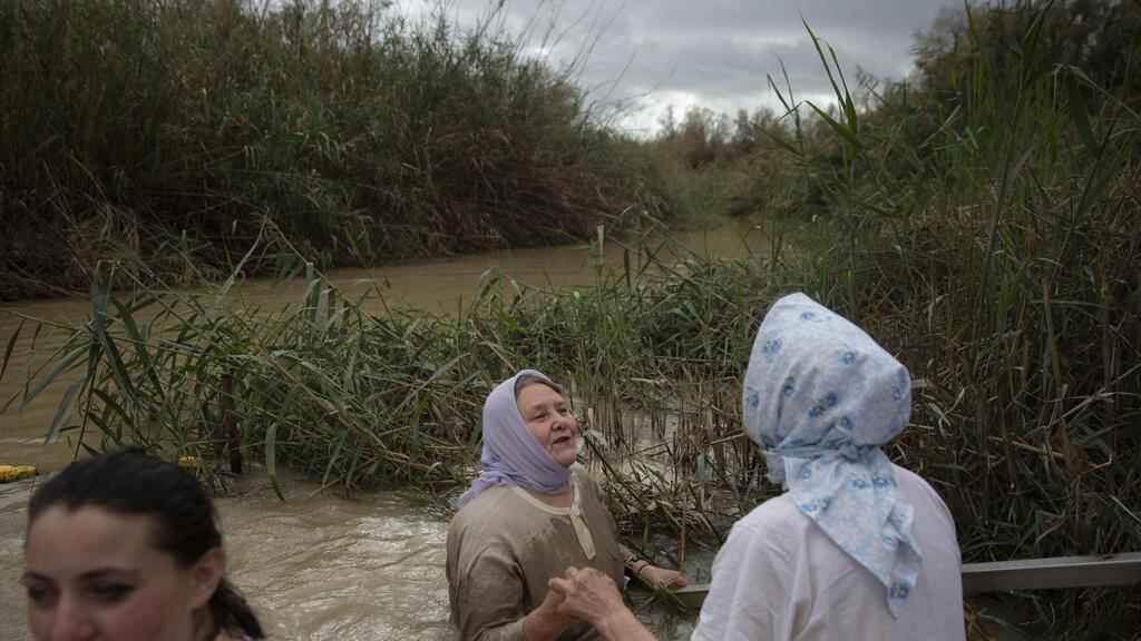 Christian pilgrims stand in the waters of the Jordan River during a baptism ceremony 