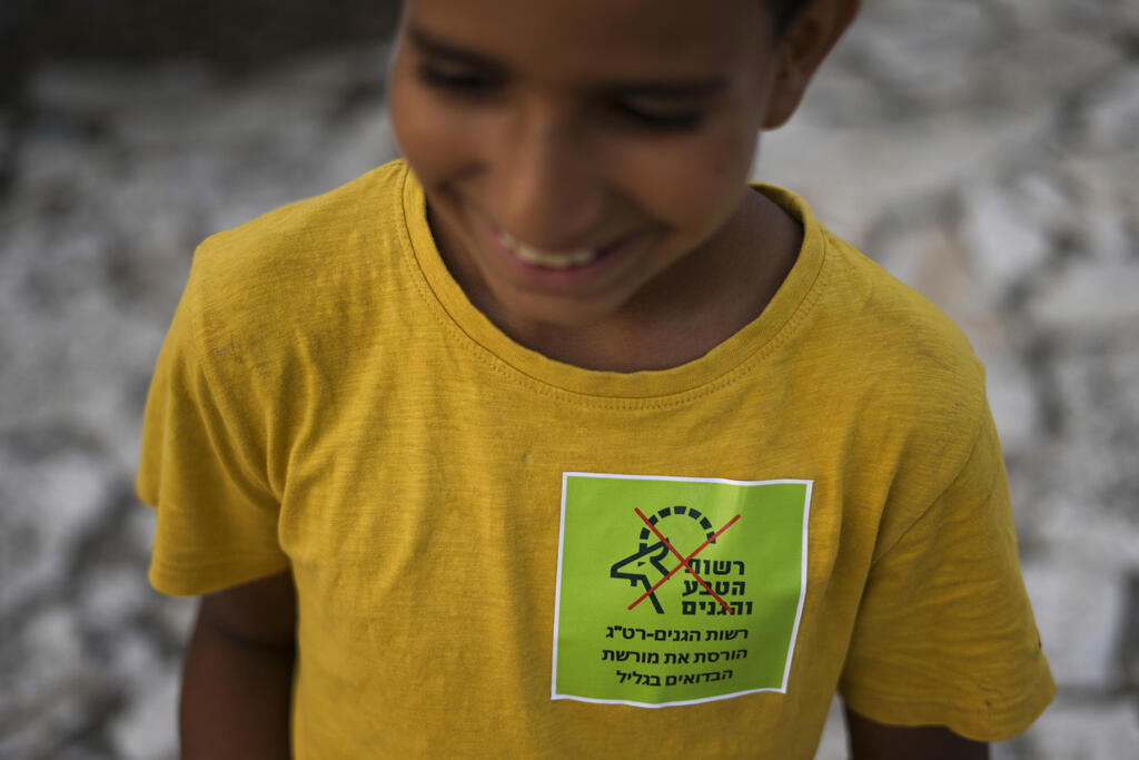 An Israeli Arab Bedouin boy wears a sticker saying 'National Parks Authority ruins the Bedouins legacy in the Galilee ' during protest in Zubeidat, Israel, Aug. 31, 2022 