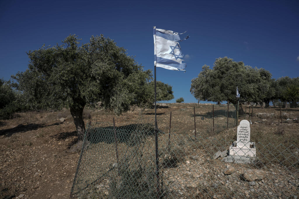 Half-torn Israeli flag held aloft in the wind in a cemetery for Bedouins who fell in the service of the State of Israel on a hillside that might soon be out of bounds to Bedouins that have grazed goats on it for generations, near Zubeidat, Israel, Aug. 23, 2022
