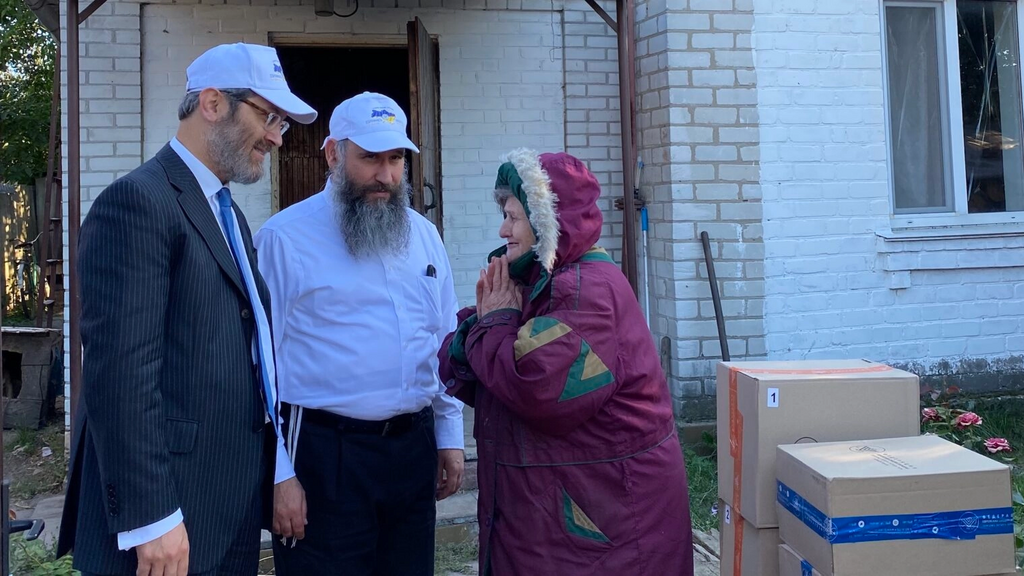 Rabbis Raphael Rotman, left, and Meir Stambler, both from the Federation of Jewish Communities of Ukraine, deliver boxes to an elderly non-Jewish Ukrainian woman in Bucha who has been receiving their aid for months 