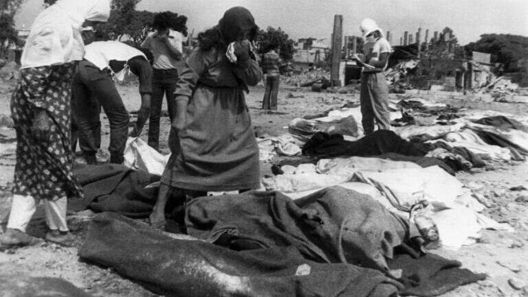 In this file photo taken on September 21, 1982, women search for their relatives among corpses 