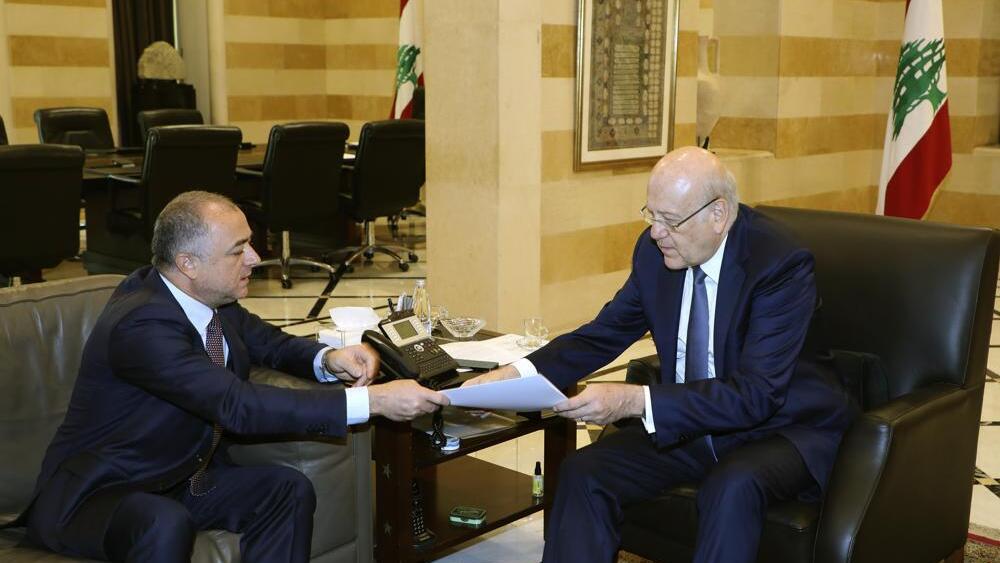 Lebanese Prime Minister Najib Makati, right, receives the final draft of the maritime border agreement between Lebanon and Israel from his deputy Elias Bou Saab who leads the Lebanese negotiating team, in Beirut, Lebanon, Tuesday, Oct. 11, 2022 