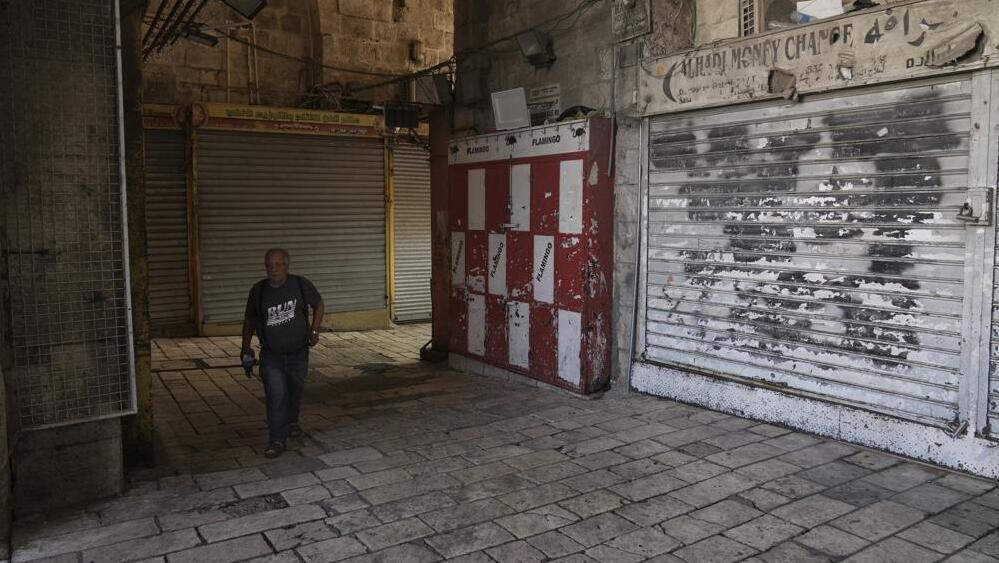 A man walks past shuttered shops in Jerusalem's Old City 