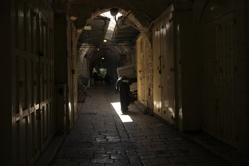 A woman walks past shuttered shops in Jerusalem's Old City 