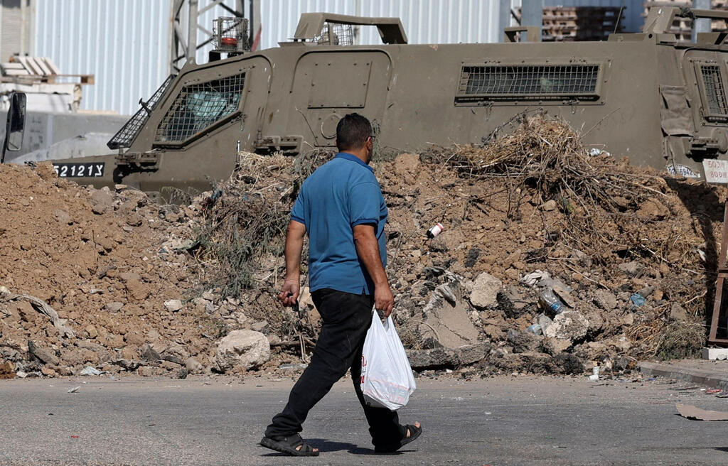 A man walks by an IDF armored vehicle after Israel blocked off entrances to Nablus 