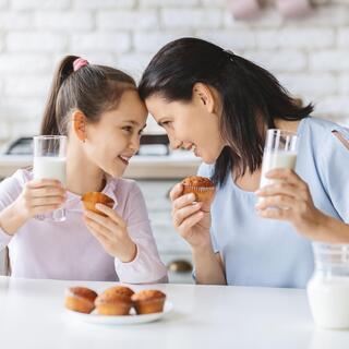 אמא ובת שותות חלב ואוכלות עוגיות מאפינס
