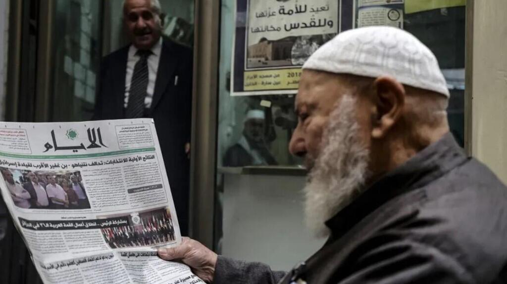 A Palestinian man reads the headlines of a local newspaper featuring the Israeli legislative at a shop in the West Bank 