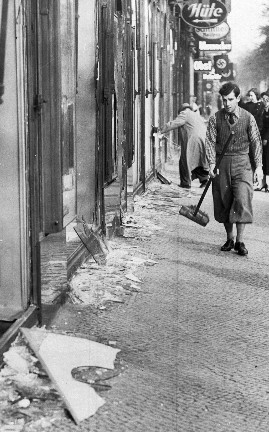 In this Nov. 10, 1938, file picture, a youth with a broom prepares to clear up the broken window glass from a Jewish shop in Berlin, the day after the ‘Kristallnacht’ rampage when Nazis set fire to hundreds of synagogues, looted thousands of Jewish businesses and attacked Jews in Germany and Austria 