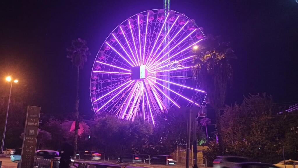 Подсвеченное фиолетовыми огнями колесо обозрения в тель-авивском луна-парке 