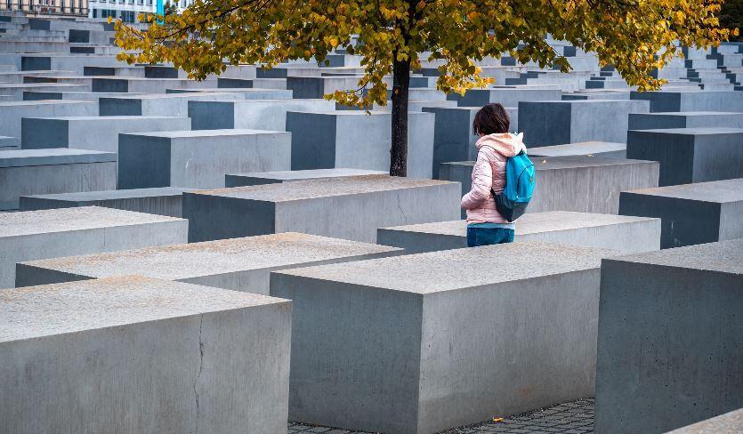 A woman stands between stelae of Holocaust memorial in Berlin