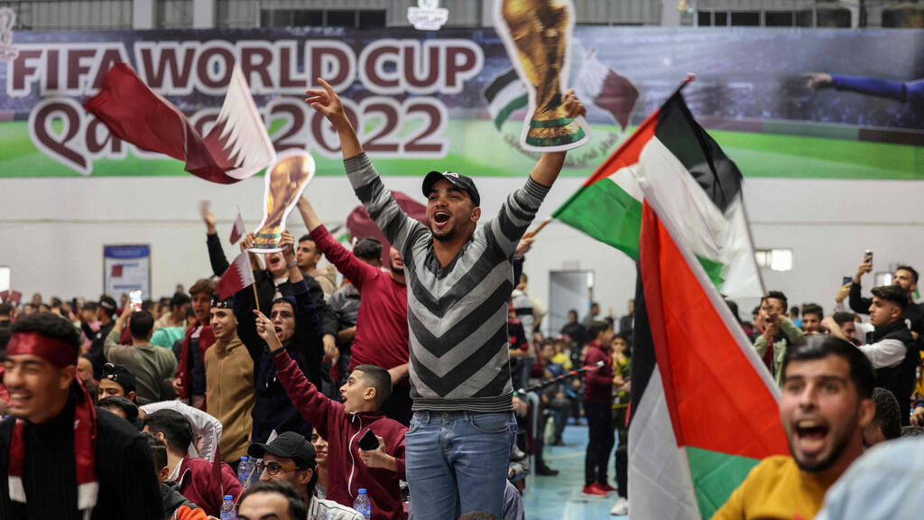 Palestinian football fans wave national and Qatari flags as they watch a live broadcast of the 2022 World Cup opening match between Qatar and Ecuador