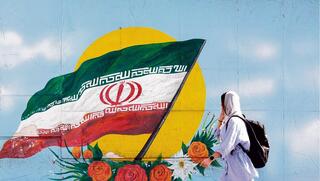צעירה בטהרן על רקע ציור קיר של דגל איראן