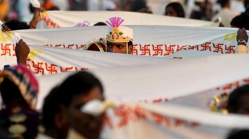 A groom stands behind a sheet bearing the Hindu swastika during a ritual at a mass wedding ceremony in Virar, on the outskirts of Mumbai, India, Sunday, Jan. 29, 2012. More than 1000 couples were married during the event that was organized by a local politician 