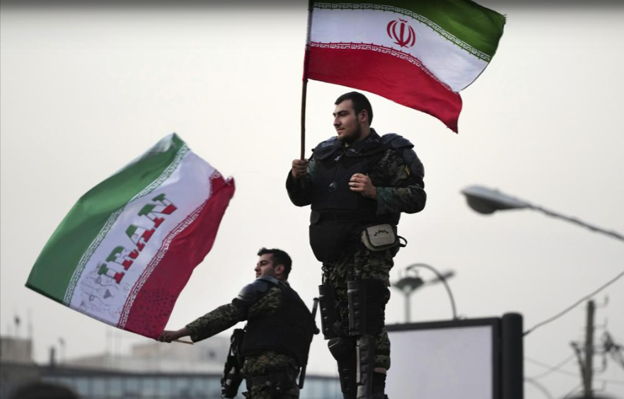 Two anti-riot police officers wave the Iranian flags during a street celebration after Iran defeated Wales in Qatar's World Cup, at Sadeghieh Sq. in Tehran, Iran, Nov. 25, 2022 