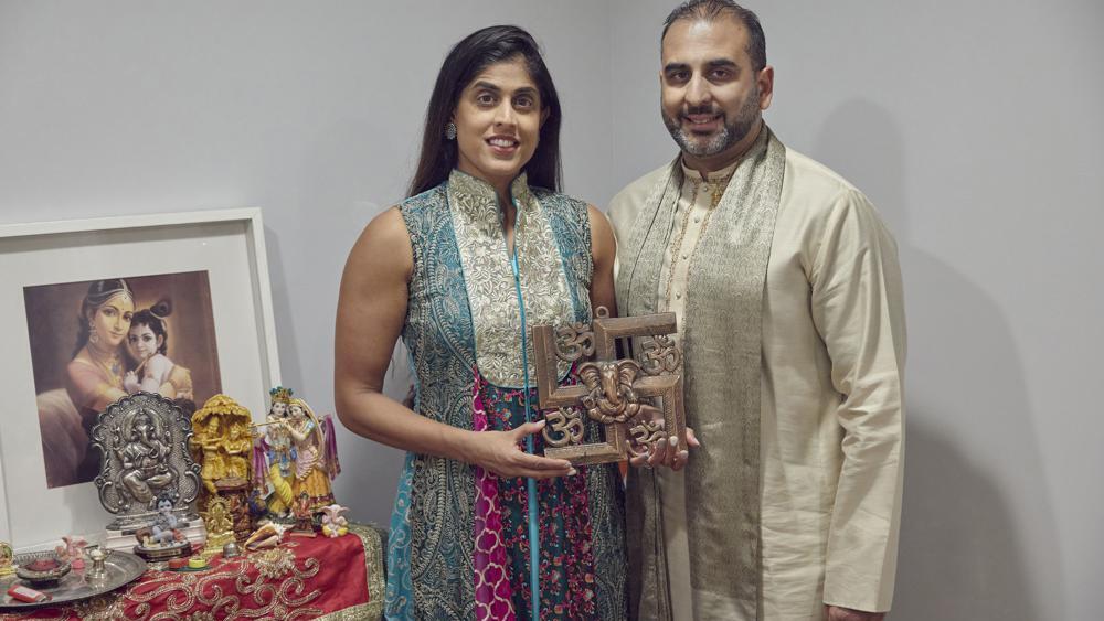 Sheetal Deo and her husband, Sanmeet Deo, hold a Hindu swastika symbol in their home in Syosset, N.Y., on Sunday, Nov. 13, 2022. Hindus, Buddhists and Native Americans are trying to rehabilitate the swastika, a symbol of peace and prosperity, and to restore it to a place of sanctity in their faiths 