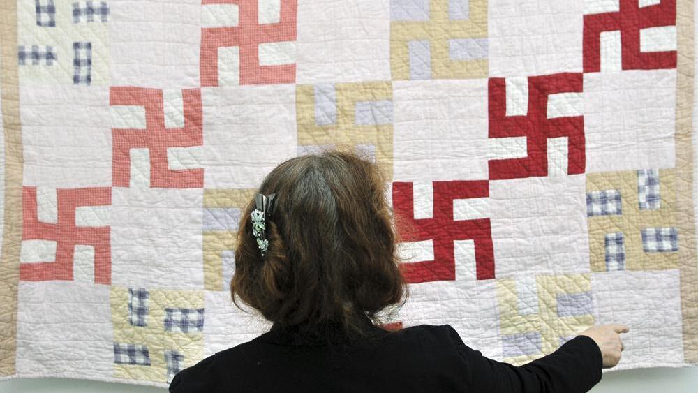 JoAnna Stull of the Greeley History Museum looks at a quilt decorated with swastikas in Greeley, Colo., on Friday June 18, 2010. The quilt was probably made before 1930, according to the family and the Greeley Museums. Hitler adopted the symbol in 1935 
