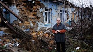 אישה עומדת ליד ביתה שהופצץ על ידי הרוסים