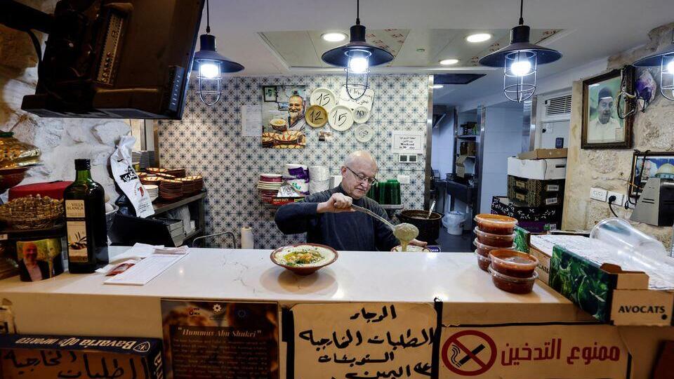 The owner of the famed Abu Shukri restaurant prepares a bowl of chickpea-based hummus in Jerusalem's Old City, December 11, 2022 