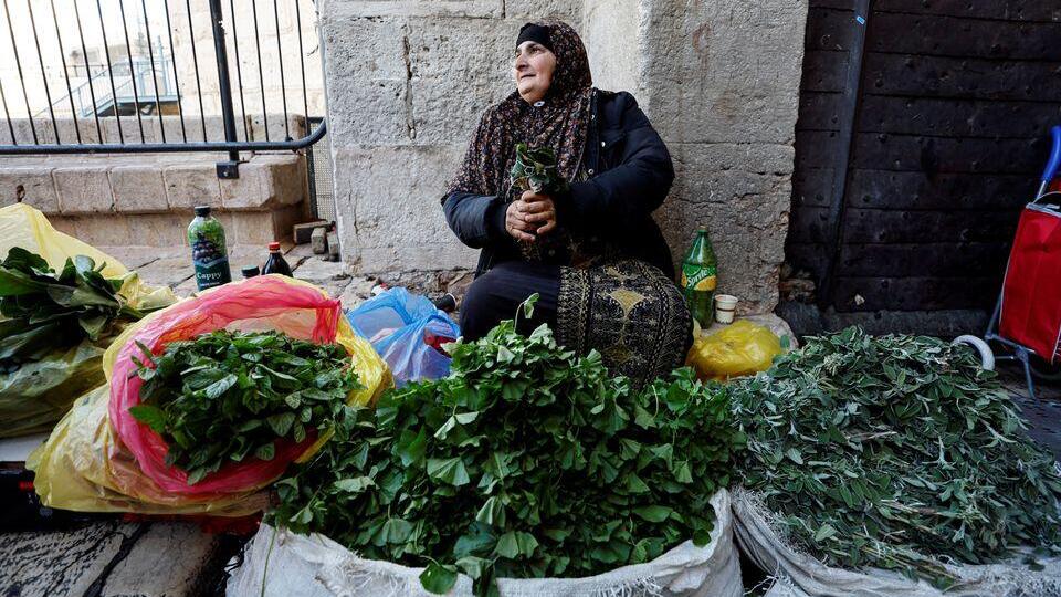 A woman sells leaves from plants used in traditional Palestinian cuisine outside Damascus Gate in Jerusalem's Old City, December 11, 2022 