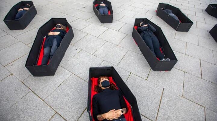 Women laying in coffins representing women killed in domestic violence 