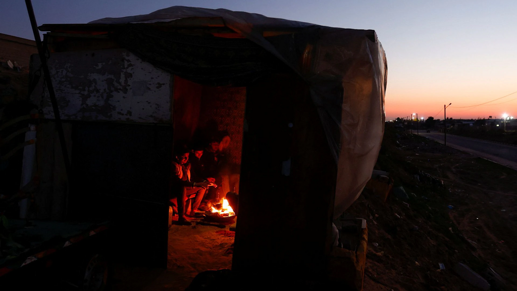 Palestinians sit around a wood fire in Khan Younis in the southern Gaza Strip, January 2, 2023 