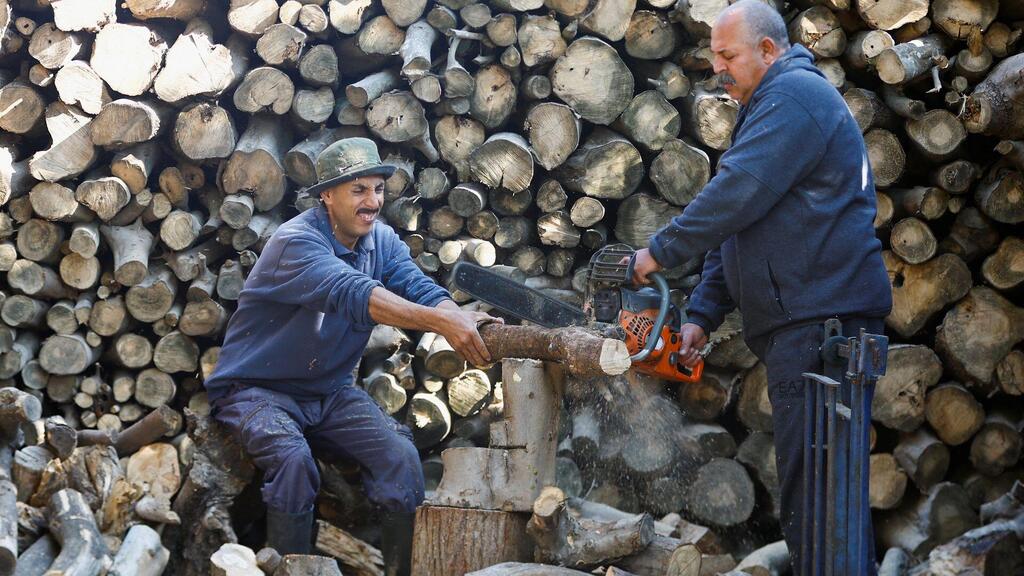A Palestinian man Samir Hejji and his son cut wood for sale, in Gaza City, December 28, 2022 