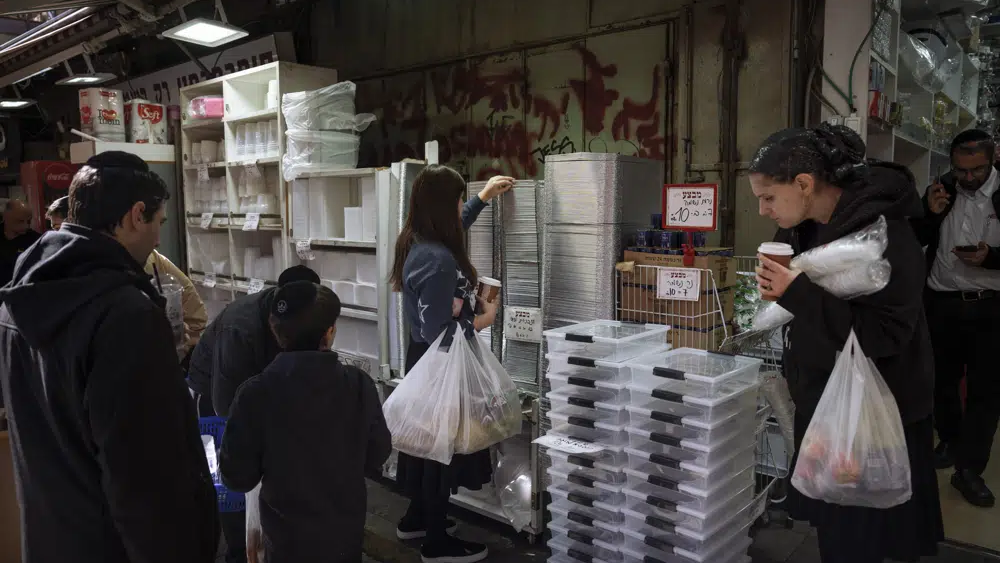 People buy disposable plastic dishes at Mahane Yehuda market in Jerusalem, Friday, Jan. 20, 2023 