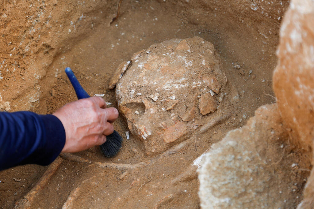 Archeologist works on remains found in a grave at the site of a 2000-year-old Roman cemetery, that had been discovered last year, in northern Gaza Strip, February 14, 2023 
