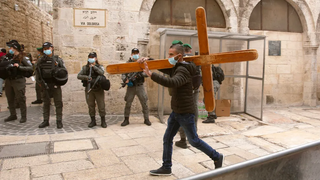 A Christian man carries a cross along the Via Dolorosa ahead of the Good Friday procession in Jerusalem's Old City 