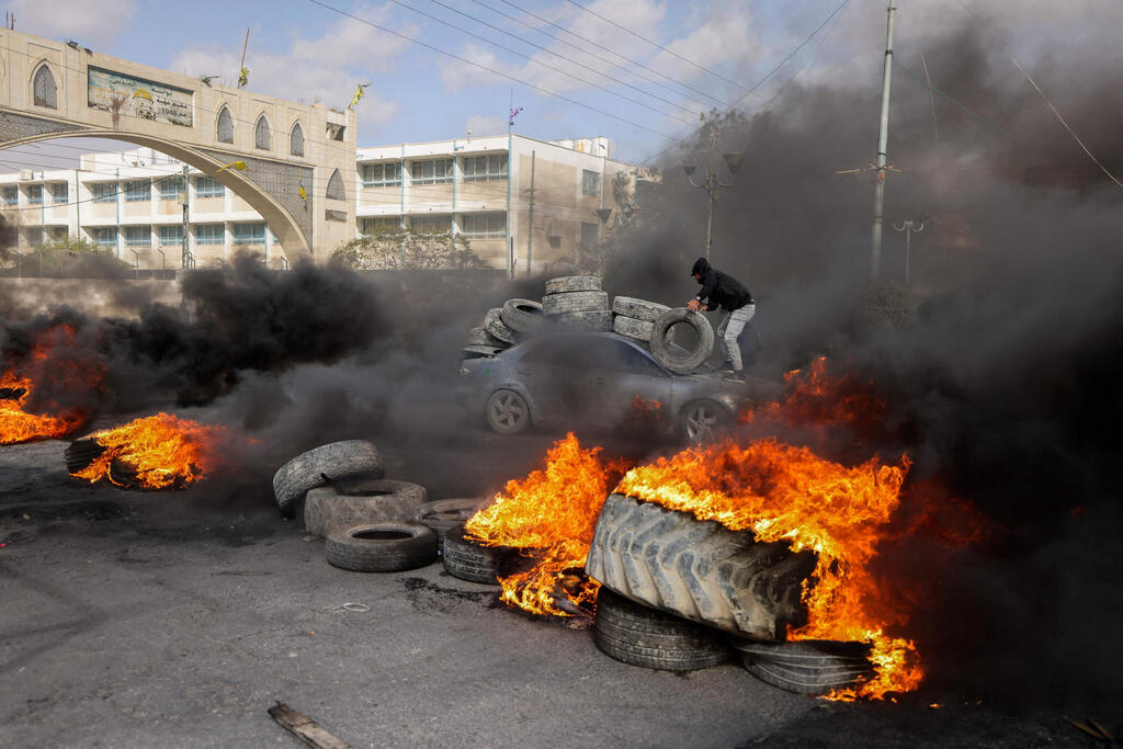 Palestinian protesters burn tyres to block a road leading into Jericho after an IDF raid last week 