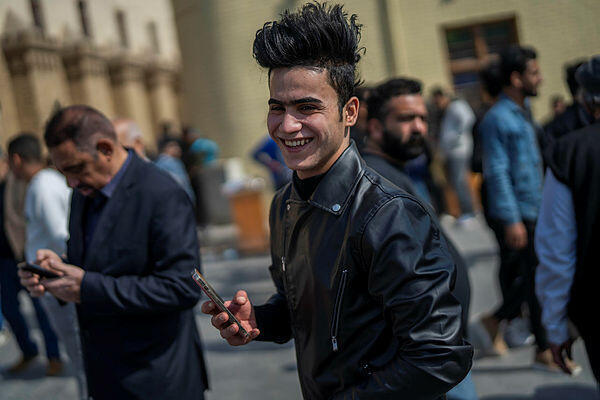 A man holds his cellphone near Al-Mutanabbi street in Baghdad, Iraq, Friday, Feb. 24, 2023