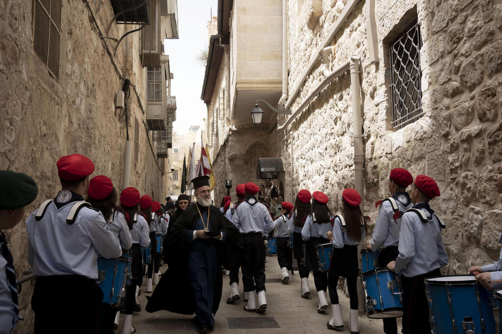 Greek Orthodox clergy member passes through a scout band procession on Orthodox Palm Sunday in the Old City of Jerusalem, April 9, 2023 