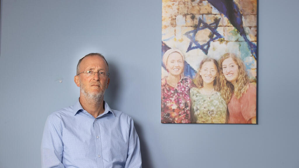 Rabbi Leo Dee next to a picture of his slain family members 